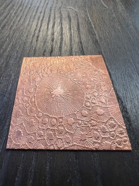 Embossed copper sheet with intricate circular patterns.
