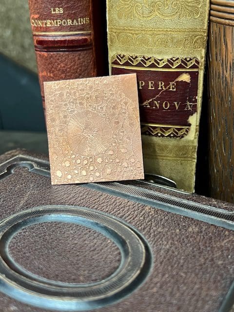 Vintage book and a textured tile on a wooden surface.