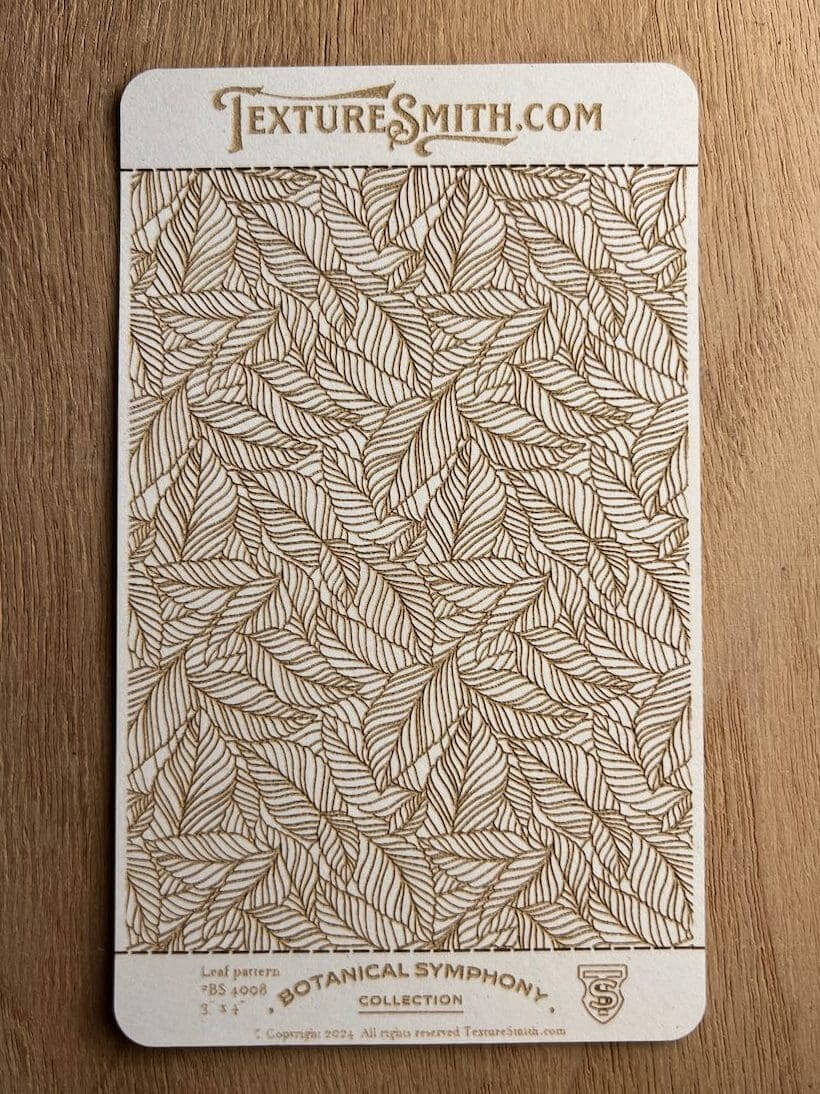 A notebook with a detailed leaf pattern cover resting on a wooden surface.