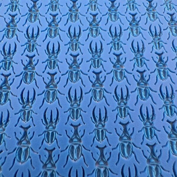 Blue fabric with black spider pattern repeating in rows.