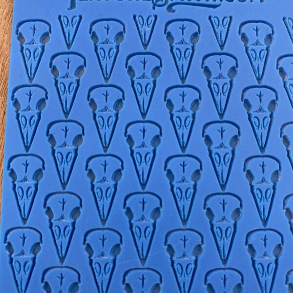 Blue fabric with repeating dark blue abstract face patterns.