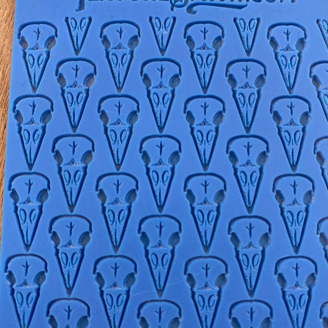 Blue fabric with repeating dark blue abstract face patterns.