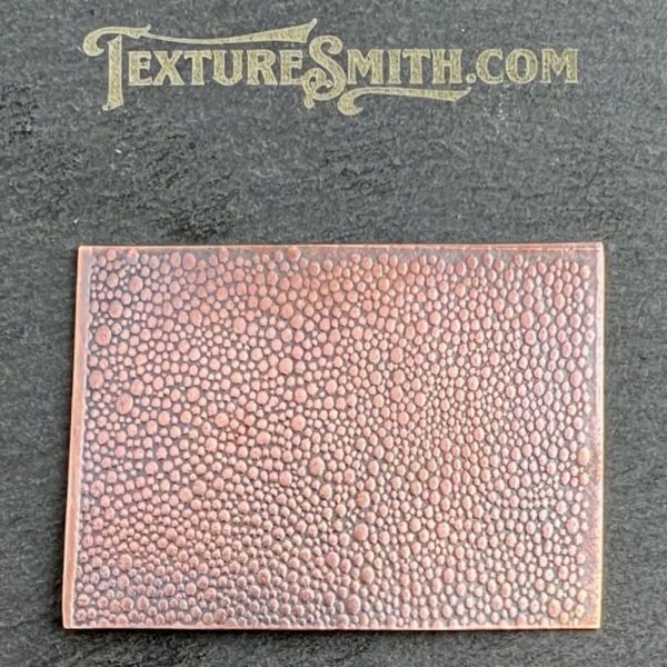 Textured brown leather piece with pebble grain pattern on a gray surface.