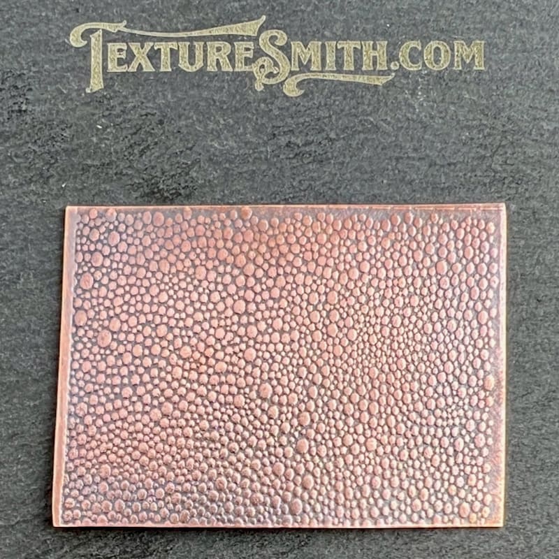 Textured brown leather piece with pebble grain pattern on a gray surface.