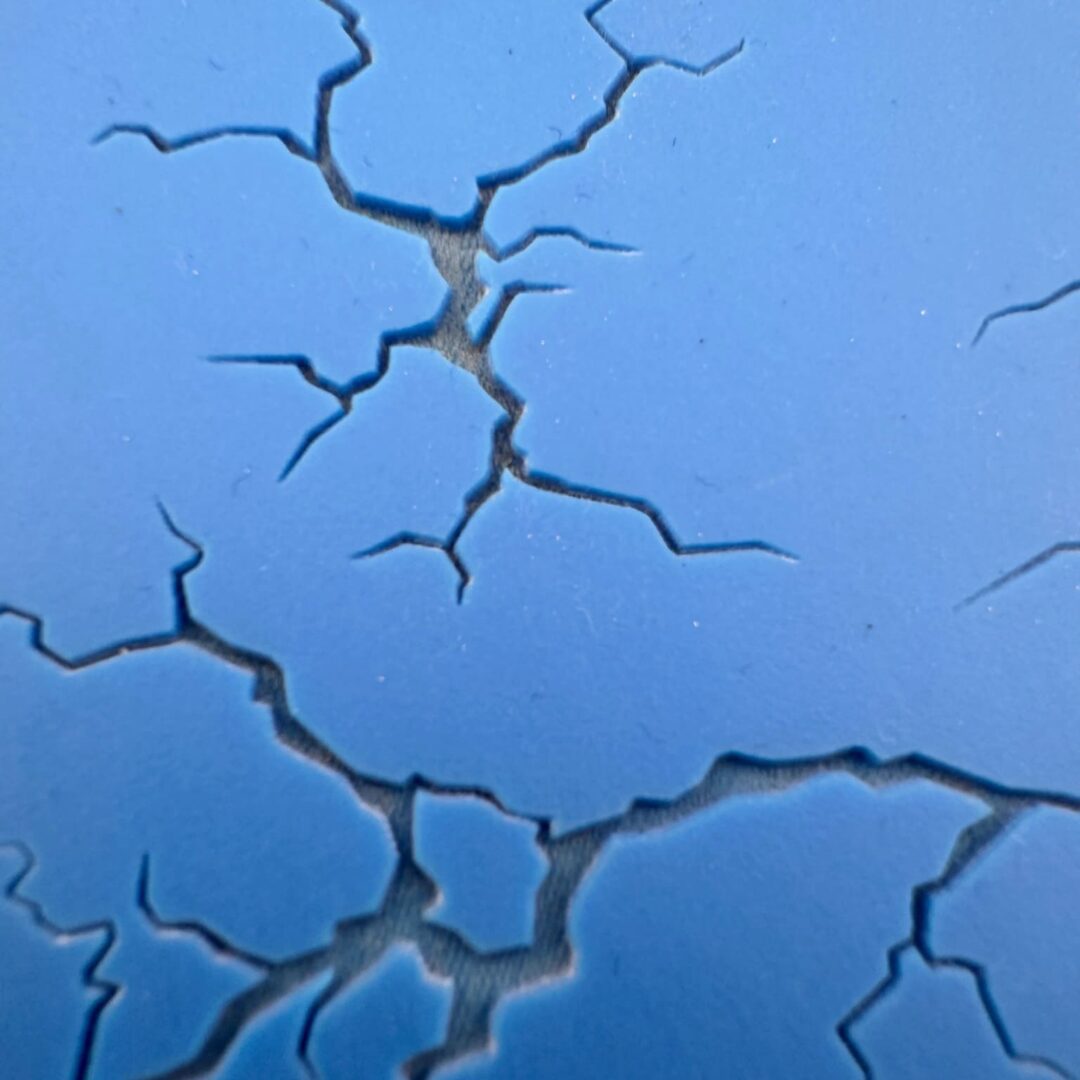 Close-up of deep cracks on a blue surface.