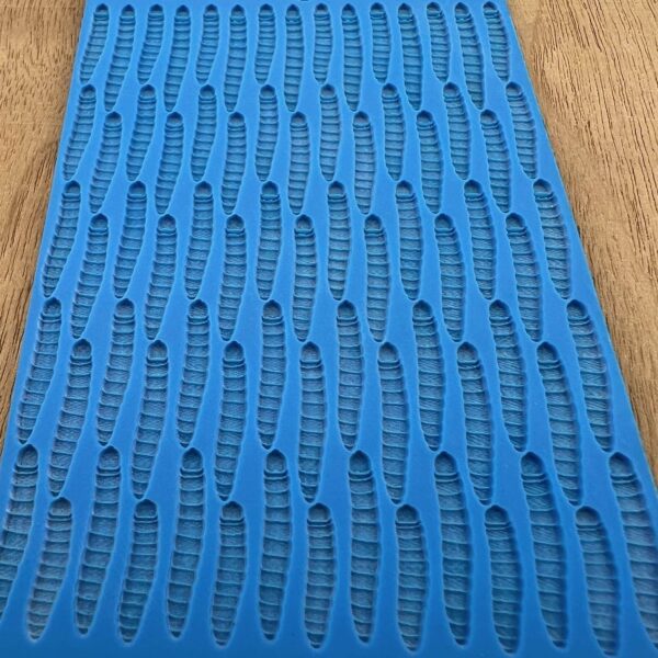 Blue textured mat with a pattern of elongated holes on a wooden surface.