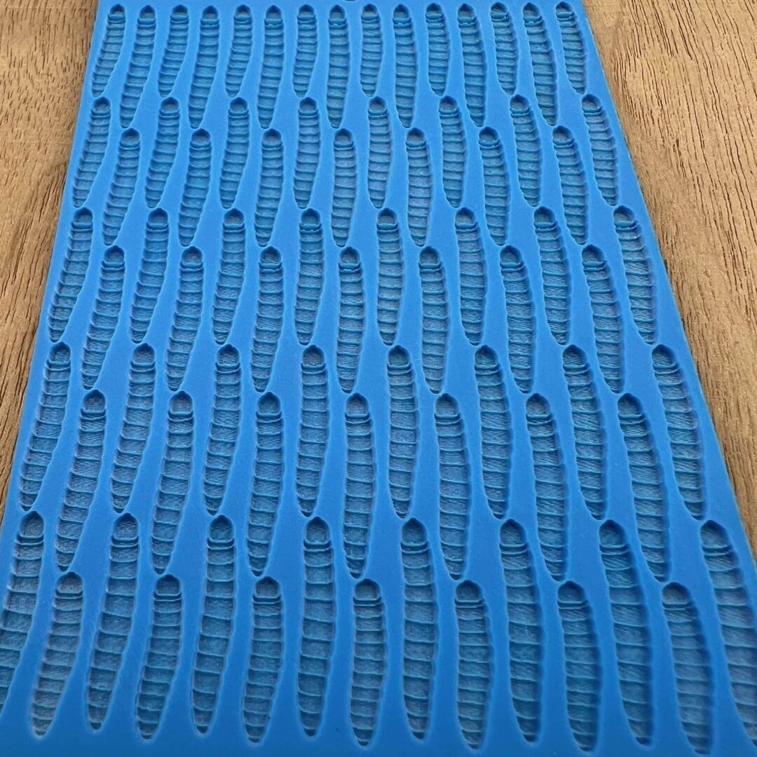 Blue textured mat with a pattern of elongated holes on a wooden surface.