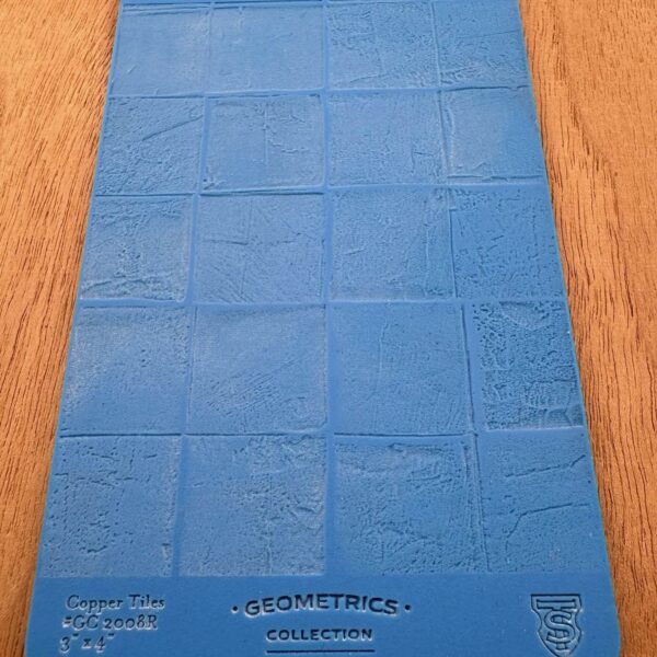 Blue silicone baking mat with embossed brick pattern on wooden surface.