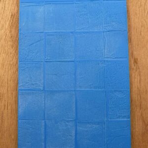Blue textured mat with a grid pattern on a wooden surface.