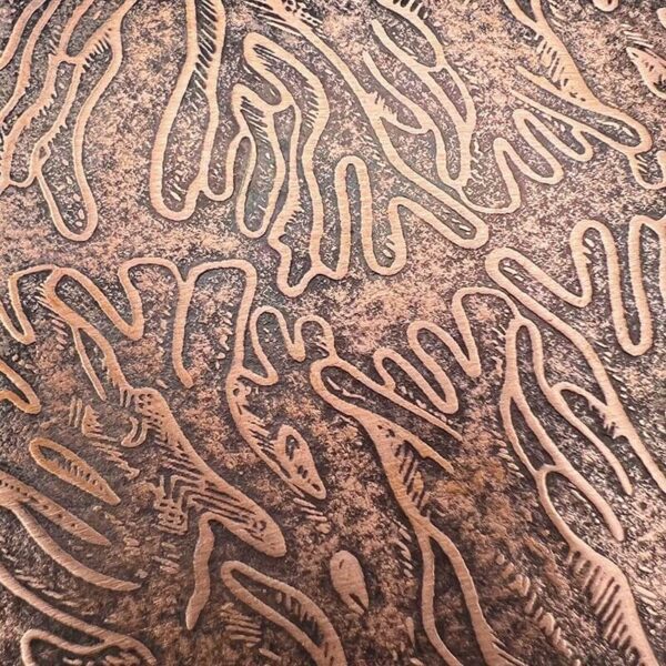 Intricate worm-like patterns etched on a textured surface.
