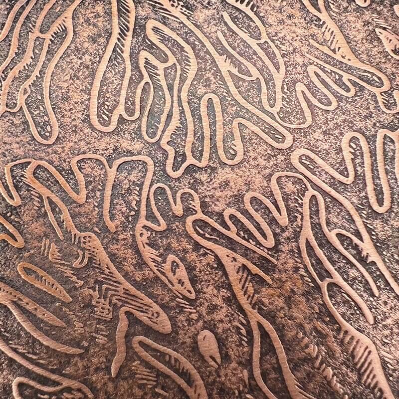 Intricate worm-like patterns etched on a textured surface.