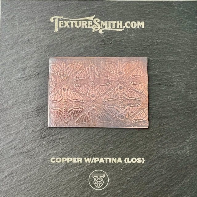Rectangular copper plate with patina and intricate geometric patterns.