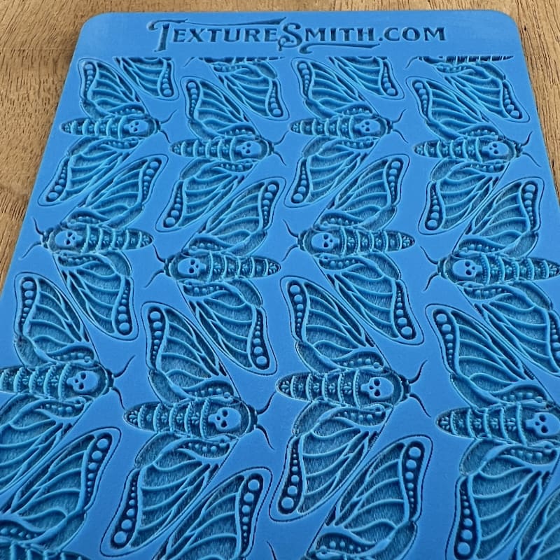 Blue stencil sheet with multiple cicada designs.