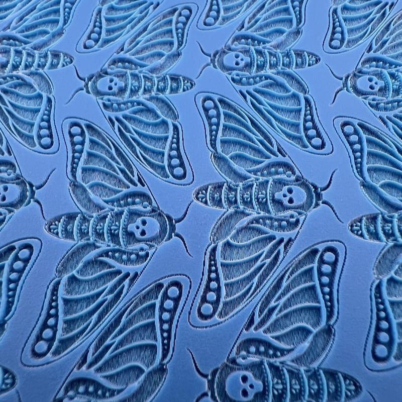 Blue fabric with intricate butterfly and leaf patterns.