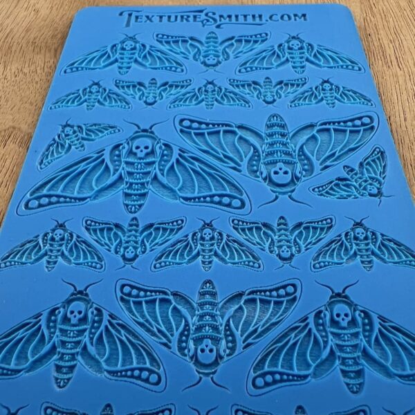 Blue fabric with black moth patterns arranged in rows.