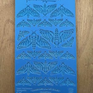 Blue stencil sheet with intricate moth designs in various sizes and patterns.