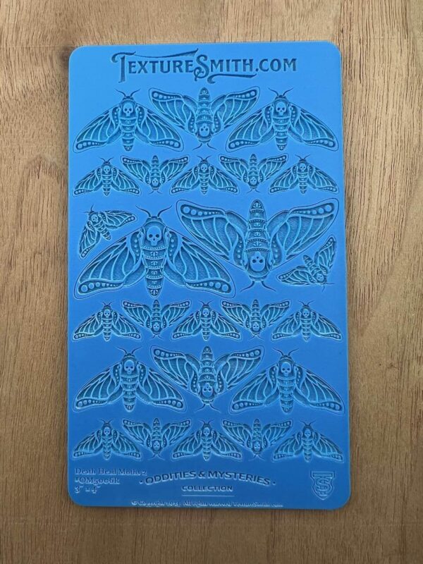 Blue stencil sheet with intricate moth designs in various sizes and patterns.