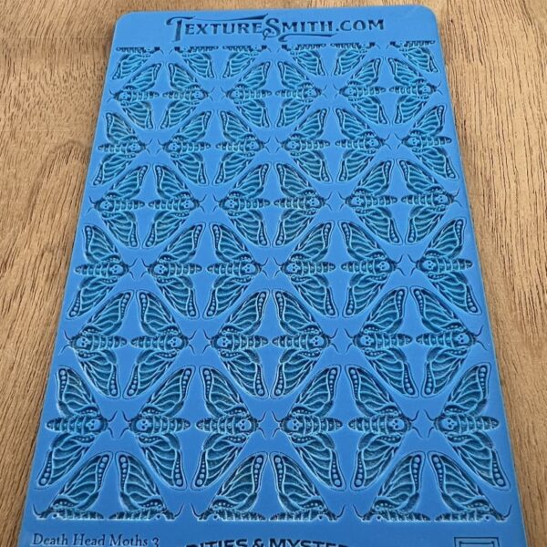 Blue stencil sheet with intricate patterns on a wooden surface.