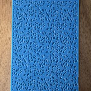 Blue textured surface with intricate leaf-like patterns on wood background.