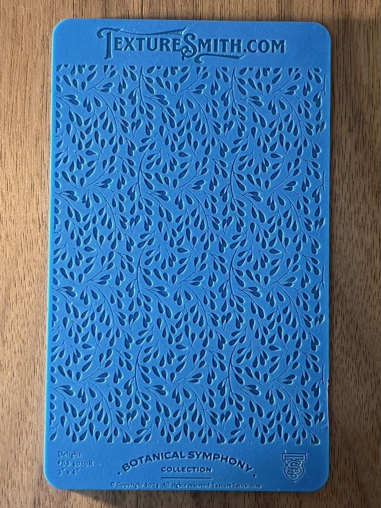 Blue textured surface with intricate leaf-like patterns on wood background.