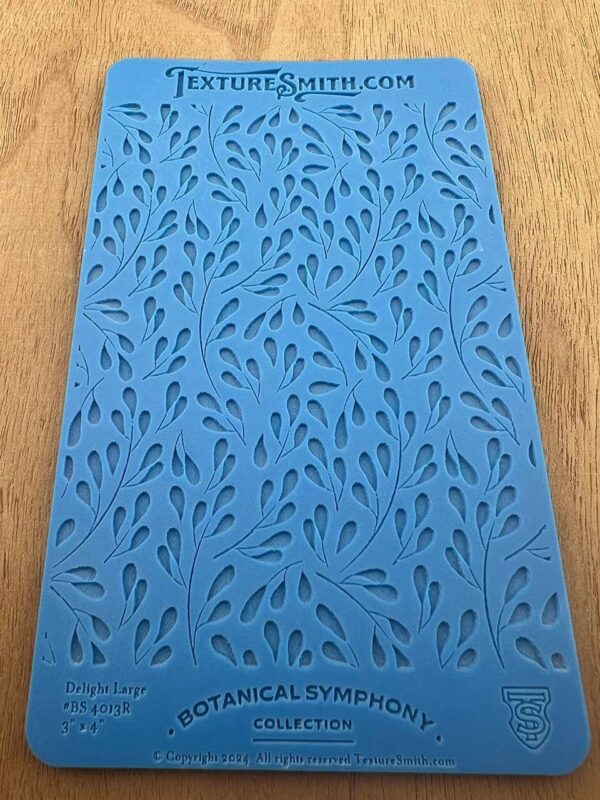 Blue stencil sheet with leaf patterns on wooden surface.