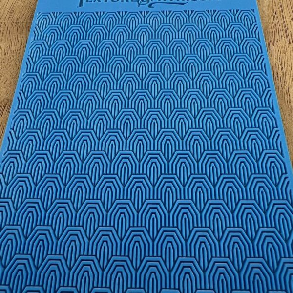 Blue mat with repeating arch patterns on a wooden floor.