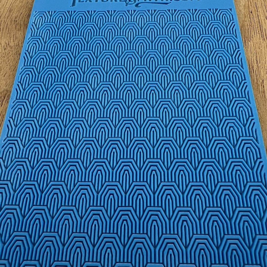 Blue mat with repeating arch patterns on a wooden floor.
