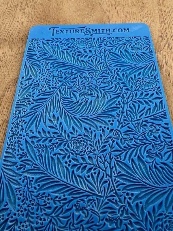 Blue fabric with intricate swirling leaf patterns on a wooden surface.