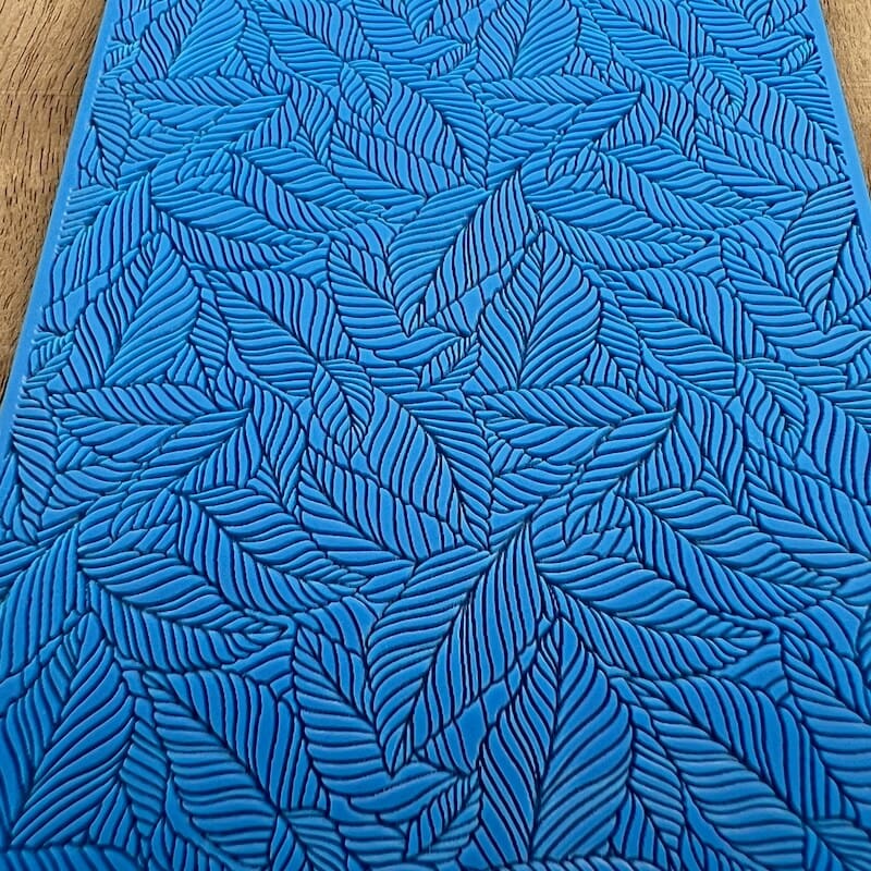Blue fabric with intricate leaf patterns in black.