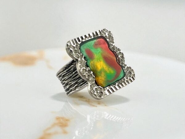 A silver ring with a vibrant, multicolored gemstone.