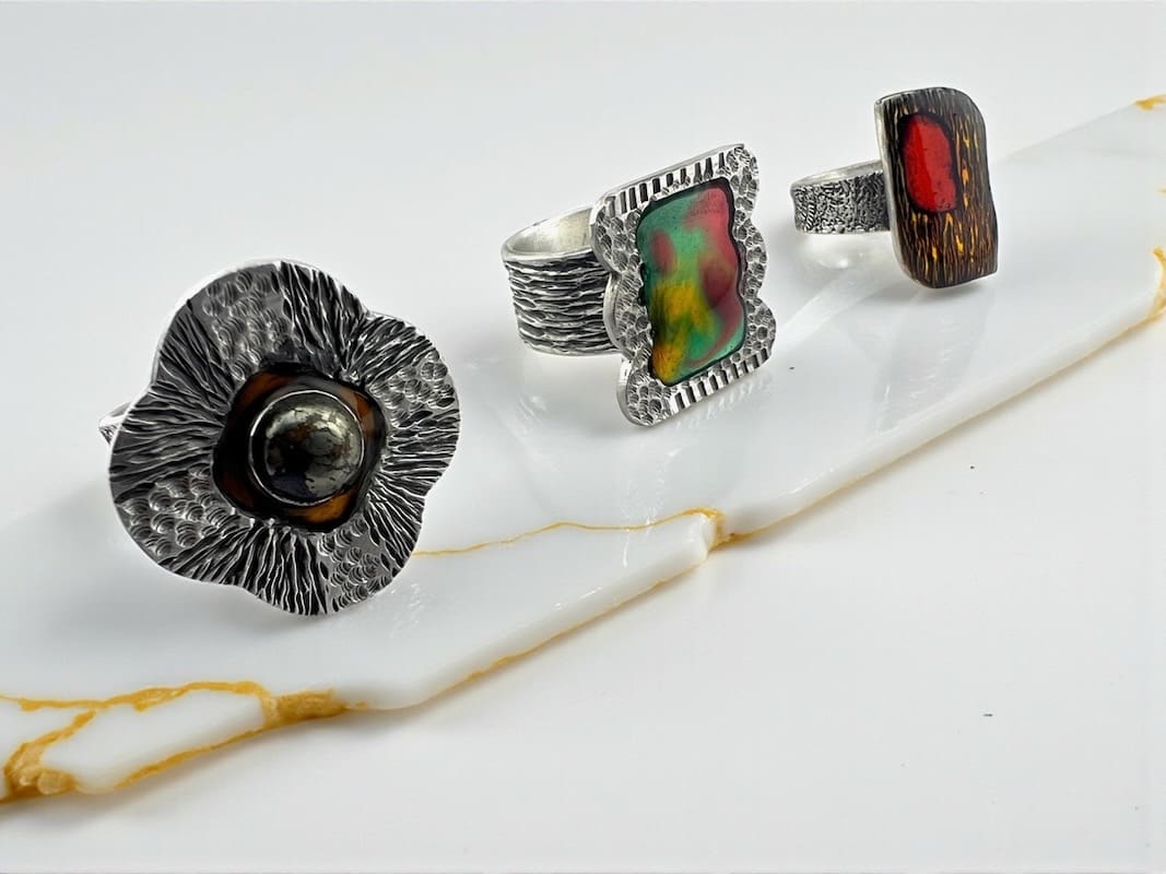 Three artistic rings with unique designs and colorful stones.
