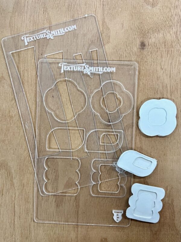 Transparent cookie cutters with blue dough imprints on wood surface.