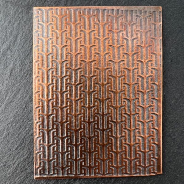 A copper plate with an intricate, repeating geometric pattern.