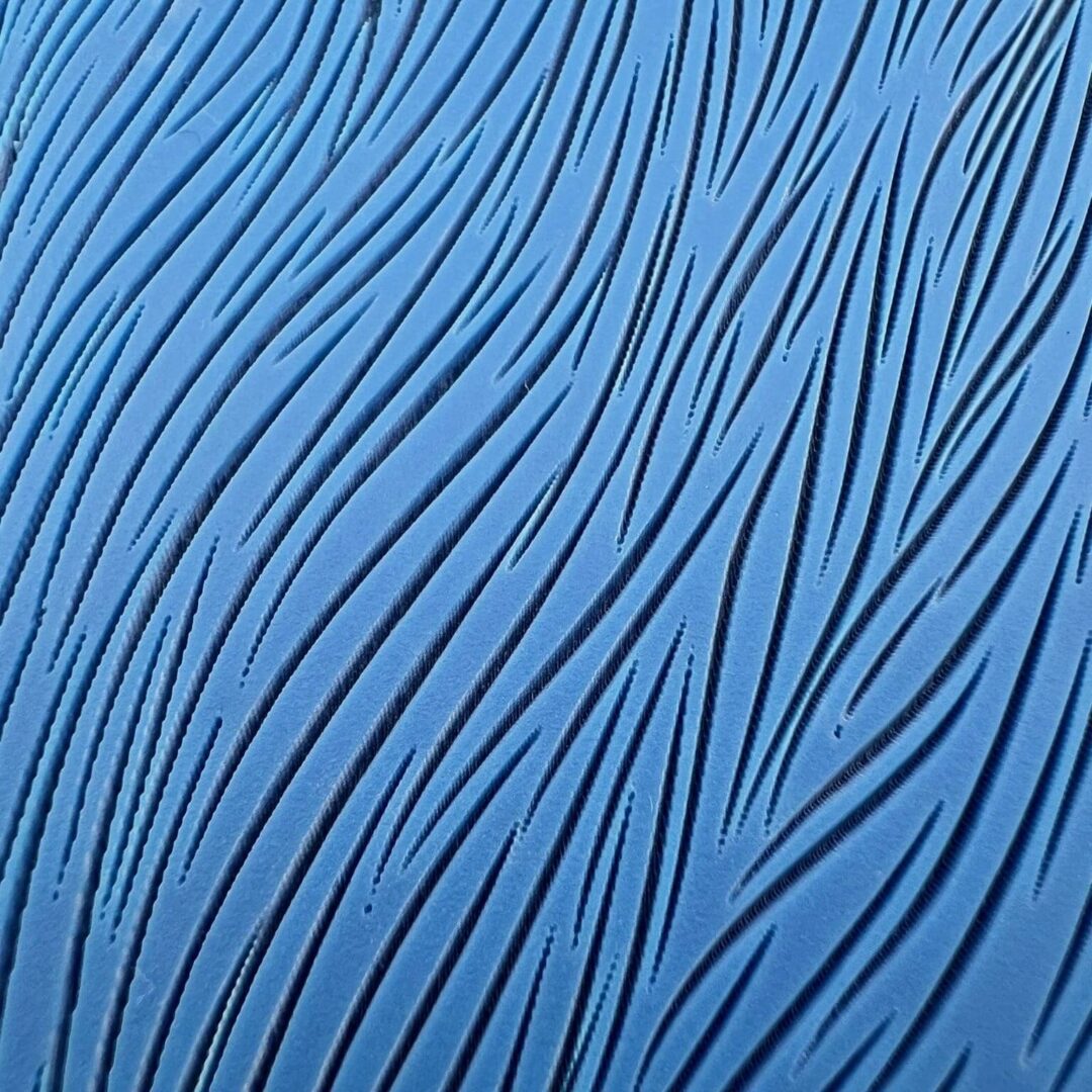 Blue surface with flowing, wave-like black lines creating an abstract pattern.