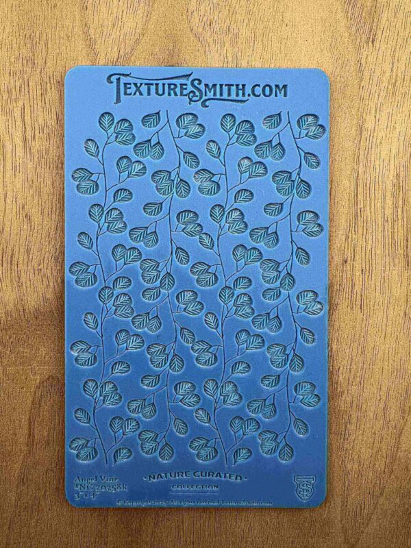 Blue stencil sheet with leafy vine patterns for crafting.