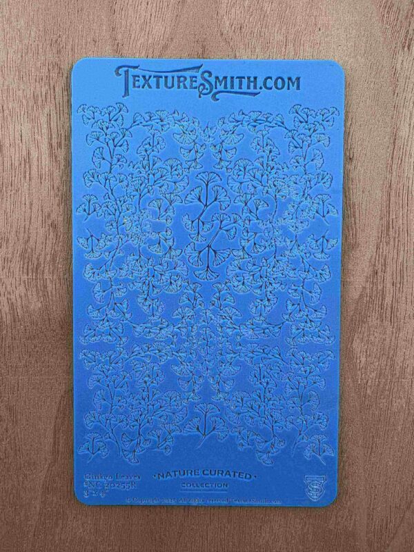 Blue stencil with intricate floral and ornamental patterns on a wooden surface.