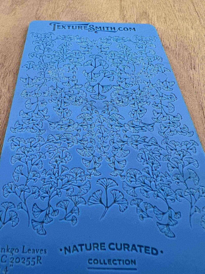 Blue silicone mat with intricate floral pattern embossing.