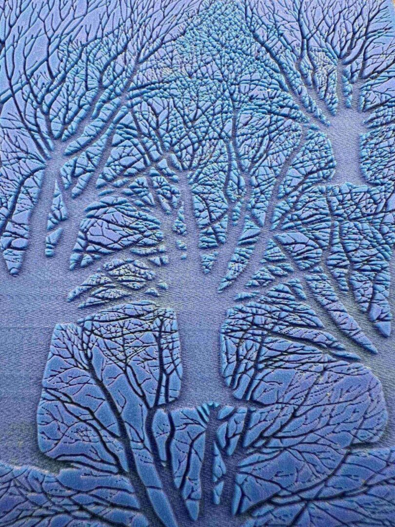 Intricate tree patterns embossed on a blue surface.