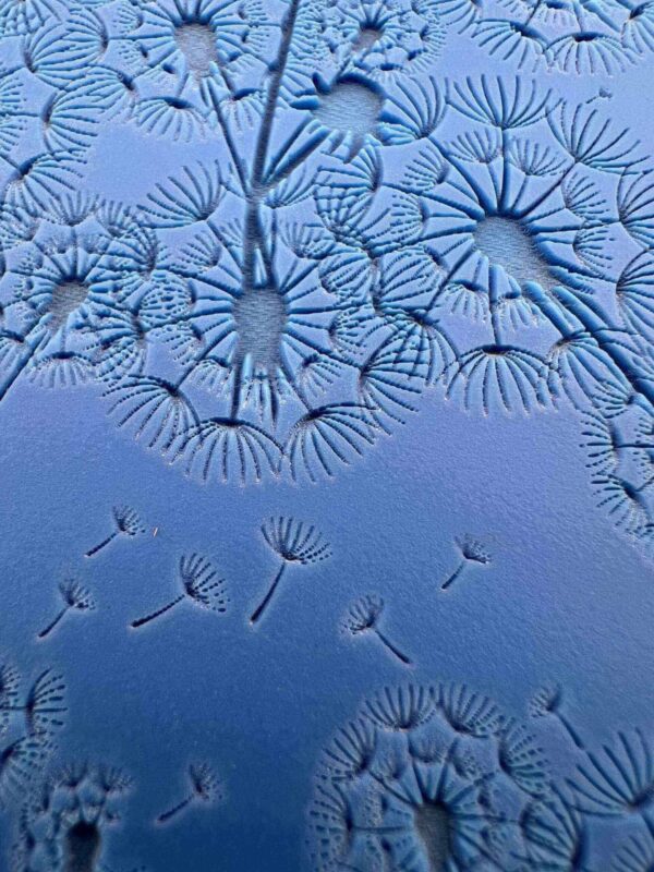 Frost patterns resembling delicate dandelion seeds on a window.
