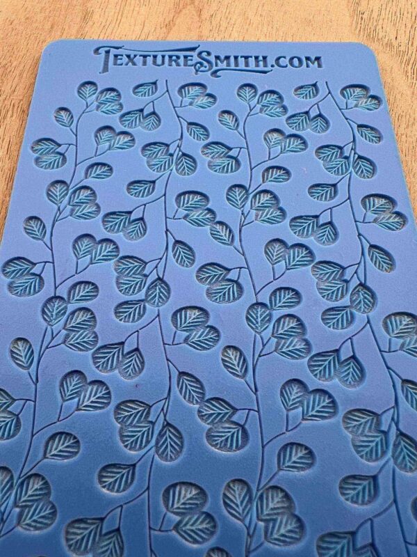 Blue fabric with a repeating pattern of black leaves and hearts.