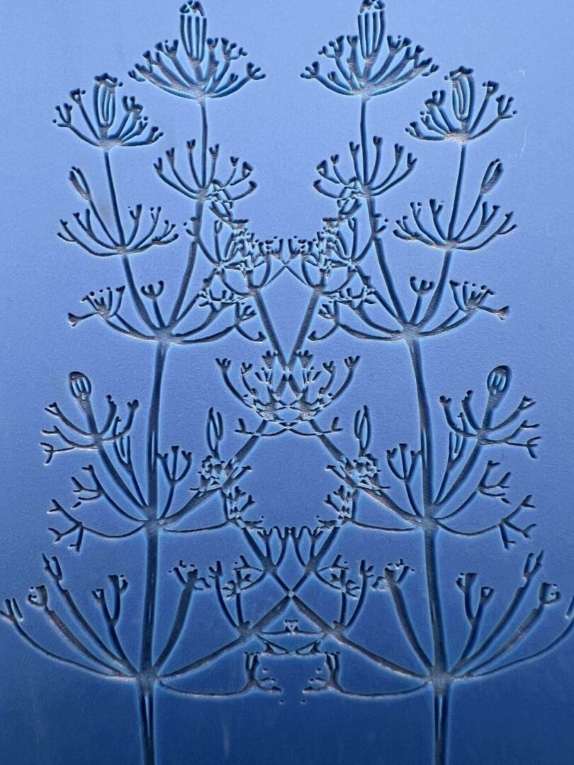 Intricate blue glass artwork with symmetrical floral patterns.