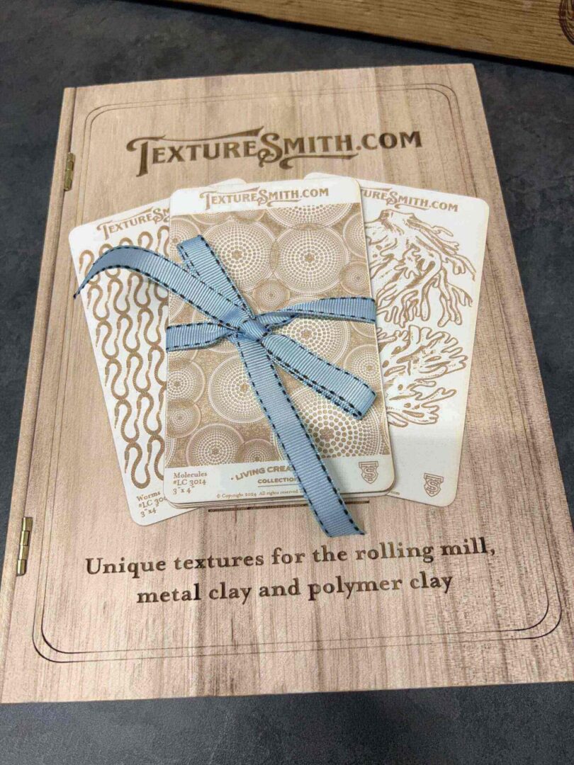 Blue metal clay ruler and square on a paper with textured patterns.