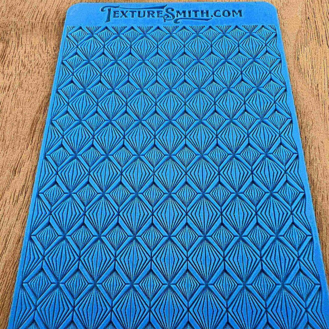 Blue textured mat with diamond and circle patterns on a wooden surface.