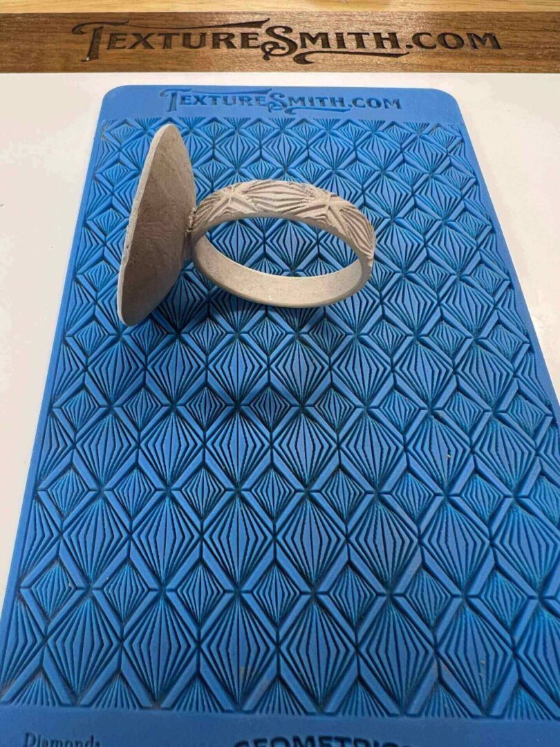 A beige ring-shaped object on a blue patterned surface.