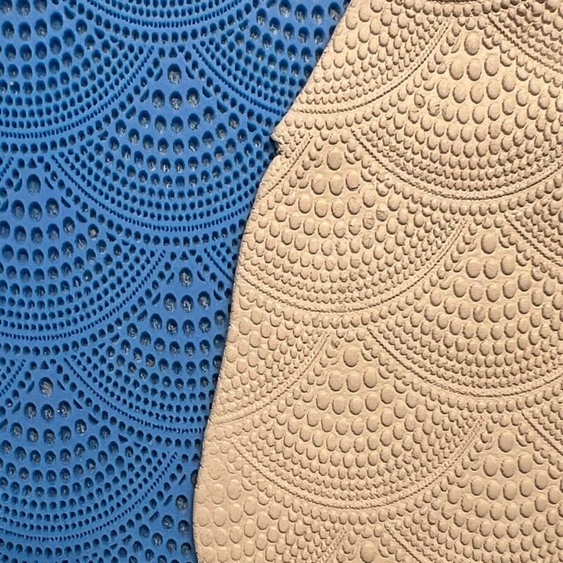 Textured blue and beige crocheted fabric with repeating semicircle patterns.