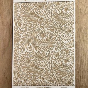 Intricate botanical pattern in beige and white on a wooden surface.