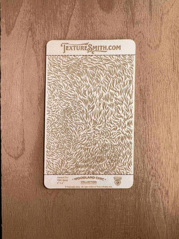 Intricate gold floral design on a card against a wooden background.