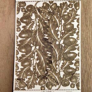 Intricate botanical woodblock print with leaves and berries in sepia tones.