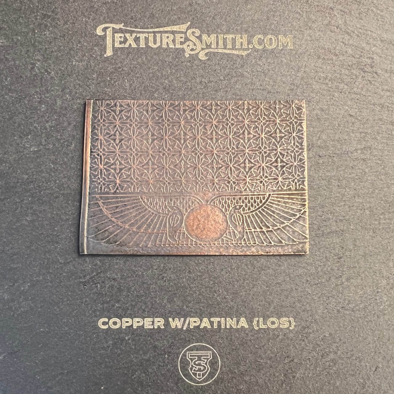 Close-up of a copper plate with a patina and embossed texture.