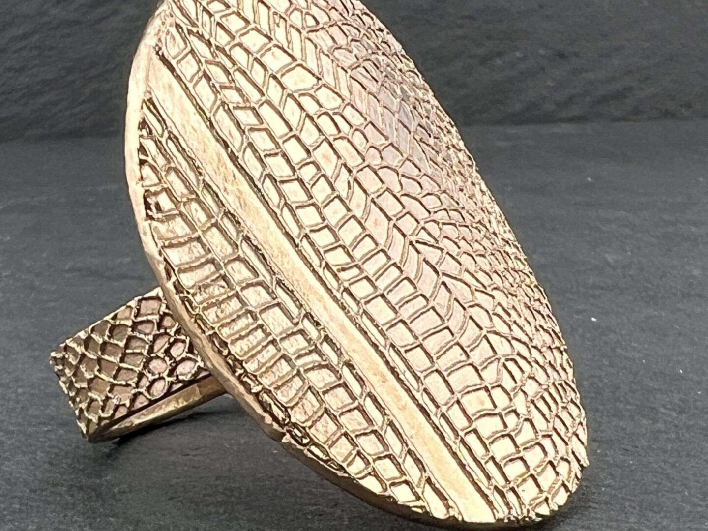 Close-up of a textured gold ring with a crocodile pattern.